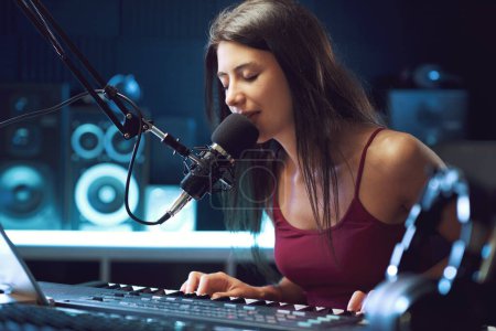 Foto de Joven artista femenina cantando y tocando el teclado en el estudio de grabación, creatividad y concepto de entretenimiento - Imagen libre de derechos