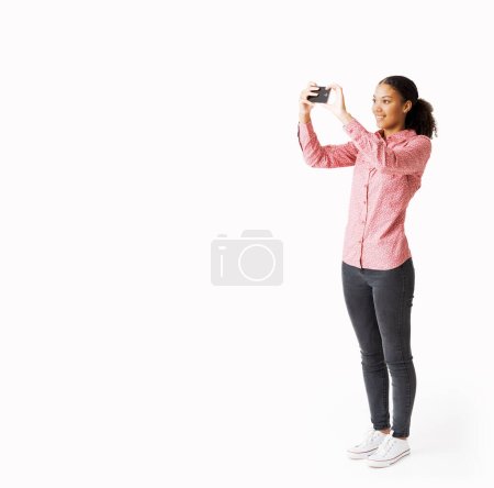 Photo for Smiling woman taking pictures with her phone and sharing online - Royalty Free Image