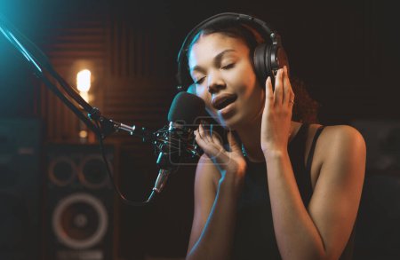 Téléchargez les photos : Jeune femme séduisante travaillant dans le studio d'enregistrement, elle chante dans un microphone - en image libre de droit