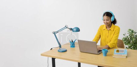 Téléchargez les photos : Jeune femme assise à son bureau et tapant sur un ordinateur portable, espace de copie - en image libre de droit