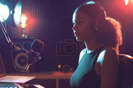 Téléchargez les photos : Jeune artiste posant dans le studio d'enregistrement, elle est assise devant le micro - en image libre de droit