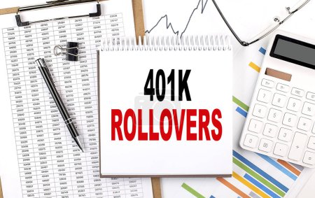 Photo for 401K ROLLOVERS text on a notebook with chart, calculator and pen - Royalty Free Image