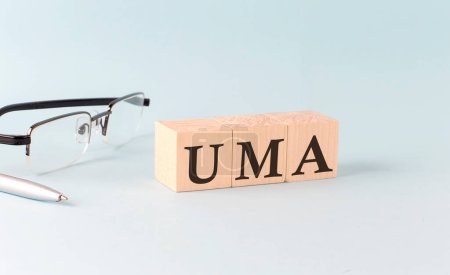 Photo for Text UMA written on wooden cubes on blue background - Royalty Free Image