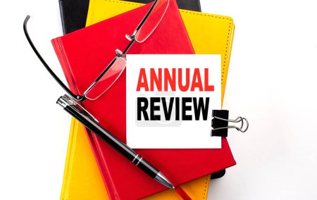 Photo for ANNUAL REVIEW text written on sticky on colorful notebooks - Royalty Free Image
