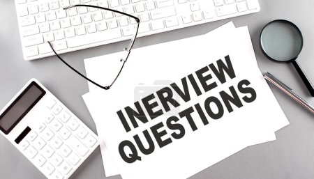 Photo for INTERVIEW QUESTIONS text on paper with keyboard, calculator on a grey background - Royalty Free Image