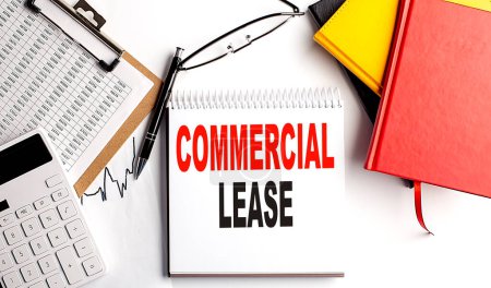 COMMERCIAL LEASE text on a notebook with clipboard and calculator on white background