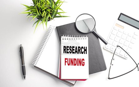 RESEARCH FUNDING text on notebook on white wooden background , business