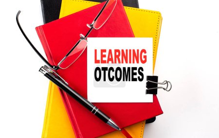 LEARNING OUTCOMES text written on sticky on colorful notebooks