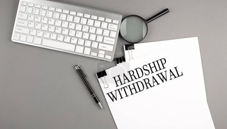 Hardship Withdrawal text on paper with keyboard, magnifier and pen. Business