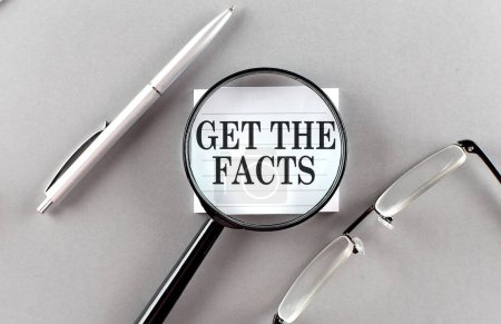 Photo for Word GET THE FACTS on a sticky through magnifier on grey background - Royalty Free Image