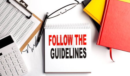 Photo for FOLLOW THE GUIDELINES text on notebook with clipboard and calculator on a white background - Royalty Free Image