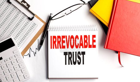 IRREVOCABLE TRUST text on notebook with clipboard and calculator on a white background