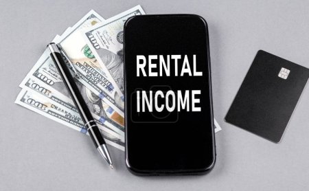 Credit card and text RENTAL INCOME on smartphone with dollars and pen. Business concept