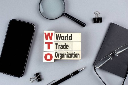 Téléchargez les photos : Wooden cubes WTO wtih notebook , magnifier and smartphone, business - en image libre de droit
