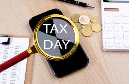 Photo for TAX DAY text on magnifier with smartphone, calculator and coins - Royalty Free Image