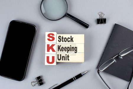 Téléchargez les photos : Wooden cubes SKU - Stock Keeping Unit wtih notebook , magnifier and smartphone, business - en image libre de droit