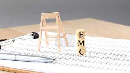 wooden cubes with the word BMC stand on financial background, business concept.