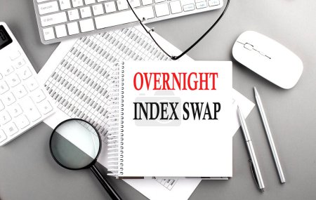 Photo for Overnight Index Swap text on notepad on chart with keyboard and calculator on a grey background - Royalty Free Image