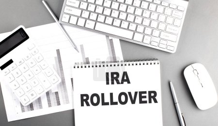 Photo for IRA ROLLOVER text written on a notebook on grey background with chart and keyboard, business concept - Royalty Free Image
