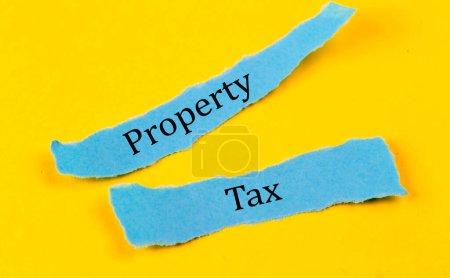 Photo for PROPERTY TAX text on blue pieces of paper on yellow background, business concept - Royalty Free Image