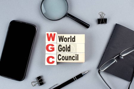 Téléchargez les photos : Cubes en bois WGC WORLD GOLD COUNCIL wtih notebook, loupe et smartphone, entreprise - en image libre de droit