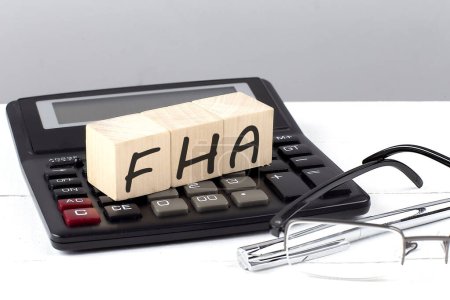Foto de Concepto FHA sobre cubos de madera en calculadora sobre fondo blanco - Imagen libre de derechos