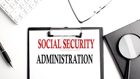 Téléchargez les photos : Social Security Administration text written on a paper clipboard with office tools - en image libre de droit
