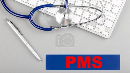 Téléchargez les photos : Mot PMS avec stéthoscope sur un clavier sur fond gris - en image libre de droit