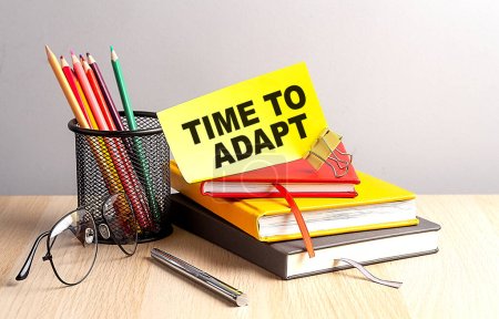 Photo for TIME TO ADAPT written on sticky on notebooks - Royalty Free Image
