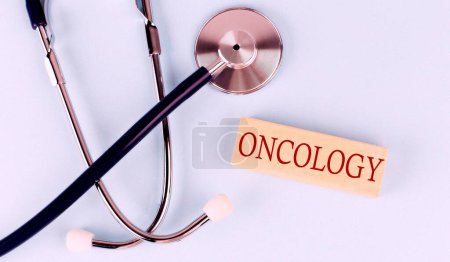 Foto de Sobre fondo azul, estetoscopio y bloque de madera con la palabra ONCOLOGÍA. Concepto médico - Imagen libre de derechos