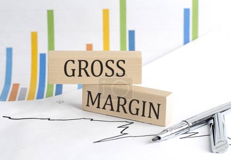 GROSS MARGIN text on a notebook with pen and pencil on grey background