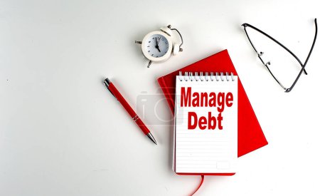 MANAGE DEBT Text auf einem Notizbuch, roter Stift und Notizbuch, Geschäftskonzept, weißer Hintergrund