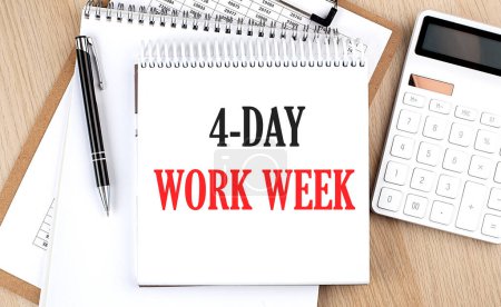 Photo for 4 DAY WORK WEEK is written in a white notepad near a calculator, clipboard and pen. Business concept - Royalty Free Image
