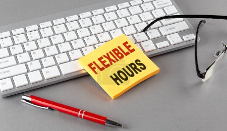 Photo for FLEXIBLE HOURS text on sticky with keyboard, pen glasses on grey background - Royalty Free Image