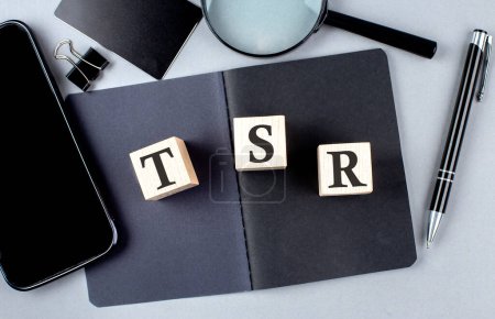 Téléchargez les photos : Word TSR sur un bloc en bois sur ordinateur portable noir avec smartphone, carte de crédit et loupe - en image libre de droit