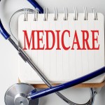 Medicare word on a notebook with medical equipment on background