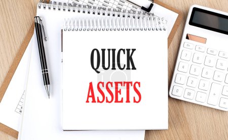 Photo for QUICK ASSETS is written in white notepad near calculator, clipboard and pen. Business concept - Royalty Free Image