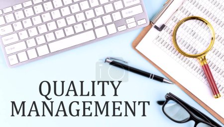 QUALITY MANAGEMENT text on blue background with keyboard and clipboard, business