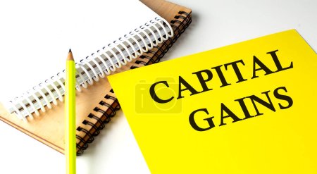 Téléchargez les photos : CAPITAL GAINS texte écrit sur papier jaune avec carnet - en image libre de droit