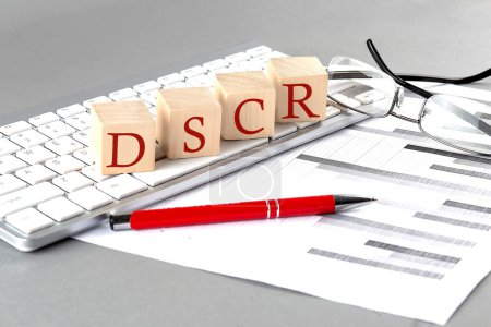 Foto de DSCR escrito en un cubo de madera en el teclado con carta sobre fondo gris - Imagen libre de derechos