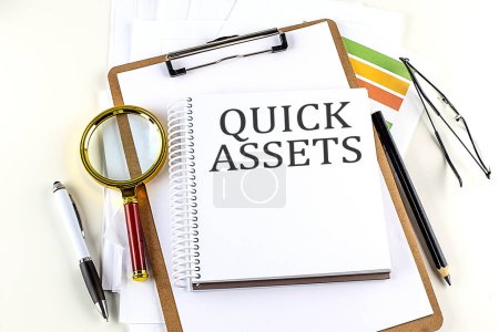 Photo for QUICK ASSETS text on a notebook with clipboard on white background - Royalty Free Image