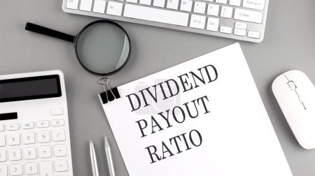 DIVIDEND PAYOUT RATIO written on paper with office tools and keyboard on grey background