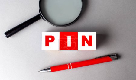 Téléchargez les photos : Mot PIN sur un cube en bois avec stylo et loupe - en image libre de droit