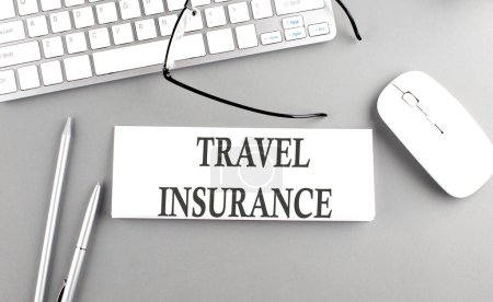 Photo for TRAVEL INSURANCE text on a paper with keyboard on grey background - Royalty Free Image
