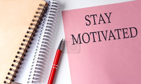 Photo for STAY MOTIVATED word on pink paper with office tools on white background - Royalty Free Image