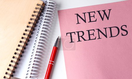 Photo for NEW TRENDS word on pink paper with office tools on white background - Royalty Free Image