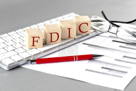 Photo for FDIC written on wooden cube on the keyboard with chart on grey background - Royalty Free Image