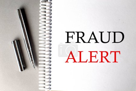 Photo for FRAUD ALERT text on notebook with pen on grey background - Royalty Free Image