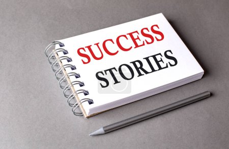 Photo for SUCCESS STORIES word on a notebook on grey background - Royalty Free Image