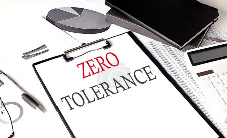 Photo for ZERO TOLERANCE text on a paper clipboard with chart and notebook on withe background - Royalty Free Image